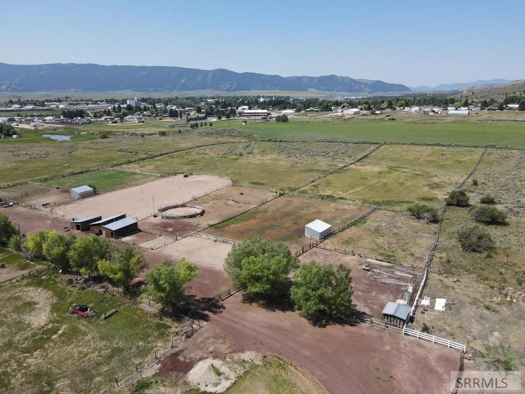 An aerial view of a horse property with barns, corrals, and an arena outside Rexburg
