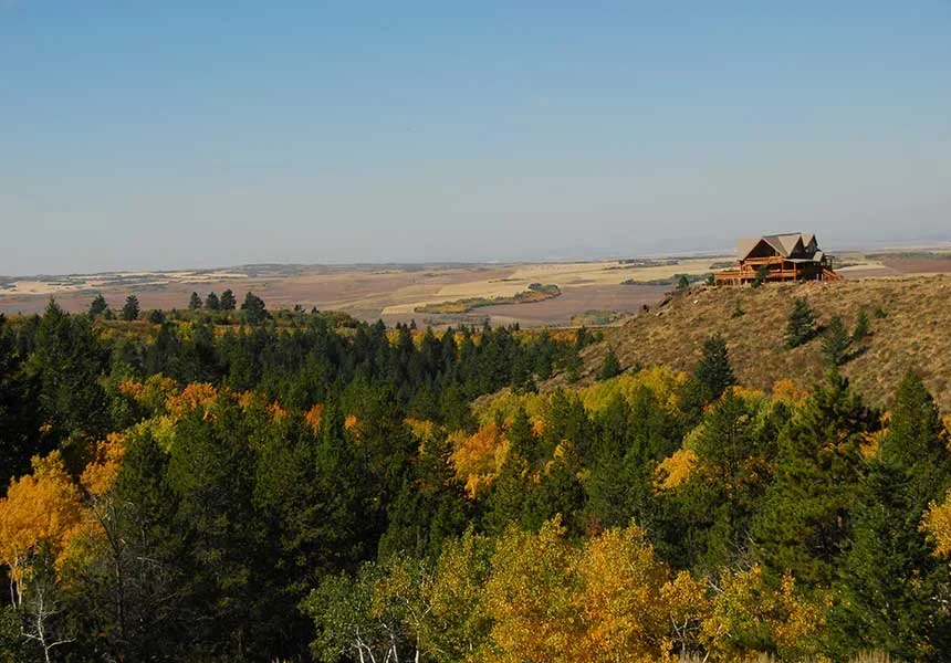 The ranch lodge on a ridge above fall aspens and the farm valley below