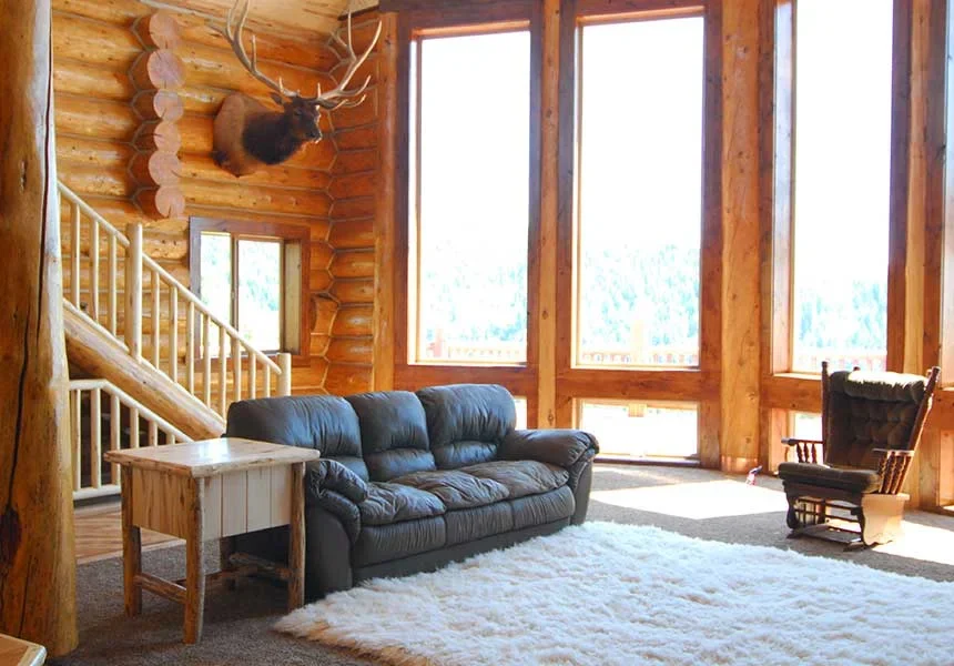 A log living room with tall windows and a leather sofa