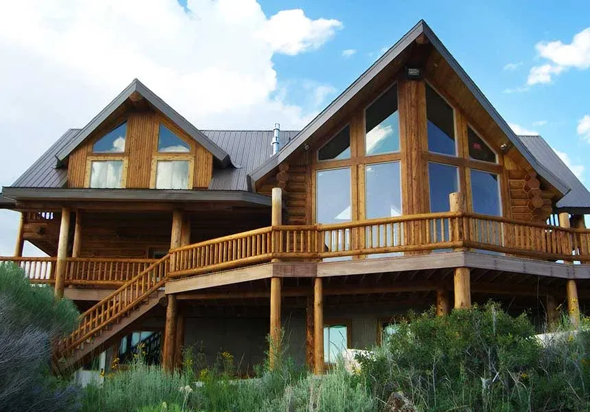 The hand-built log lodge at Rocky Mountain Elk Ranch with its wrap-around deck under a blue sky